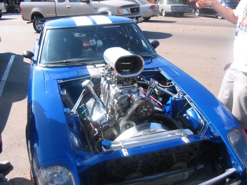 1986 Ford Bronco - A blue car with its hood open reveals a powerful supercharged engine and white racing stripes.
