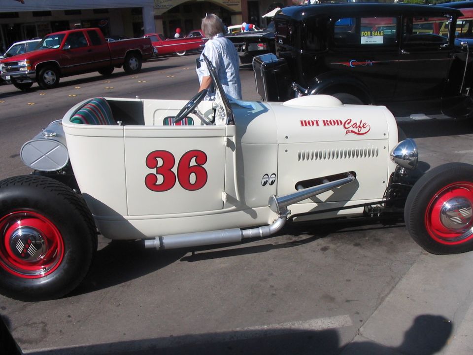 White hot rod with red number 36 and 'HOT ROD CAFE' text. Black sedan in background has 'FOR SALE' sign