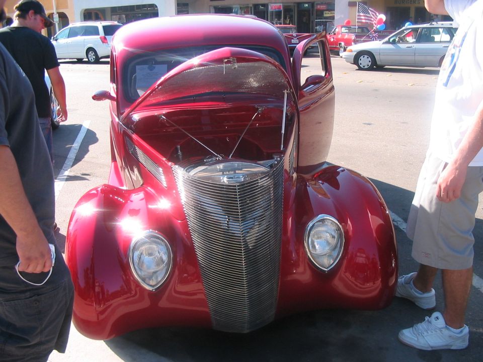 Red hot rod with hood open, showing chrome grille and exposed engine