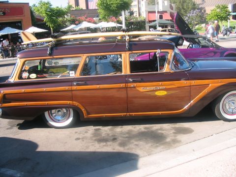 1986 Ford Bronco - Wood-paneled 1959 Ford Country Squire station wagon carries surfboards on its roof rack.