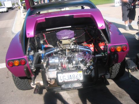 1986 Ford Bronco - Rear view of a custom purple vehicle with its engine and trunk open, revealing a modified V8 engine and a license plate.