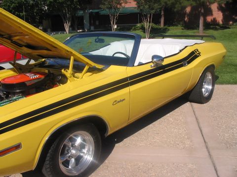 1986 Ford Bronco - A yellow convertible muscle car with black racing stripes and RT badging is parked outdoors.