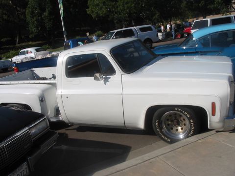 1986 Ford Bronco - Side view of a white pickup truck, likely from the 1970s, with aftermarket wheels.