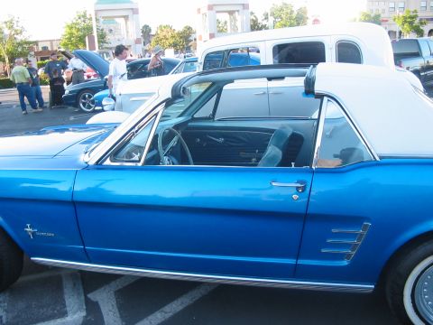 1986 Ford Bronco - A classic blue convertible is parked next to other vehicles in a lot.