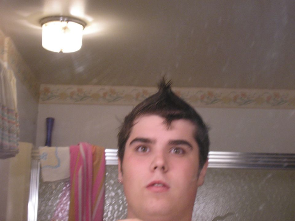 Person with mohawk hairstyle in bathroom, reflection in mirror