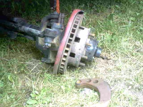 1976 Chevrolet C/K Pickup - Front axle assembly with brake rotor lying on the grass.