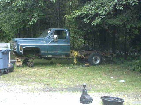 1976 Chevrolet C/K Pickup - This Chevrolet C/K Pickup chassis is missing its front wheels and rear bed, sitting in a grassy area.
