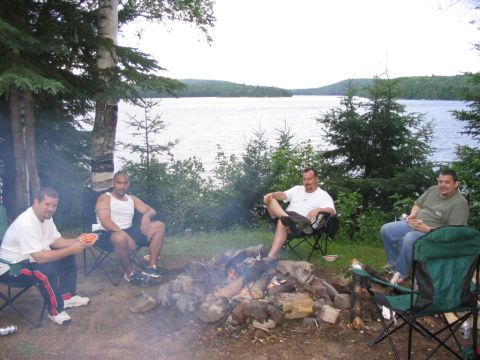 1986 Ford Bronco - Friends enjoy a campfire gathering by the water on a cloudy day.
