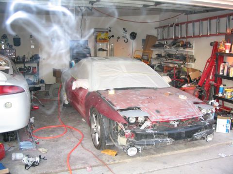 1994 Buick Park Avenue - Two cars are in a garage, one undergoing repairs with its hood covered.