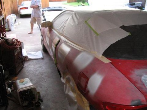 1994 Buick Park Avenue - A red car is covered in masking tape and primer patches, indicating it is undergoing repairs.