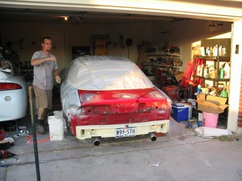 1994 Buick Park Avenue - Man working on a red car in a garage, with another white car nearby. The red car's rear is being prepped for paint.