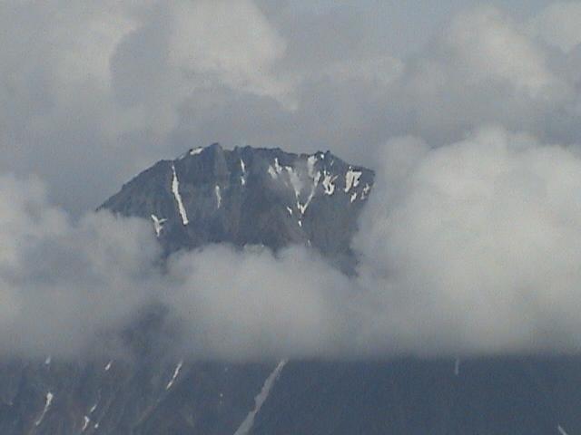 Mountain peak shrouded in clouds, with patches of snow
