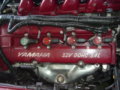 1993 Ford Taurus - Close-up of a red engine cover displaying "YAMAHA 32V DOHC 3.4L" with visible ignition coils and wiring harnesses.