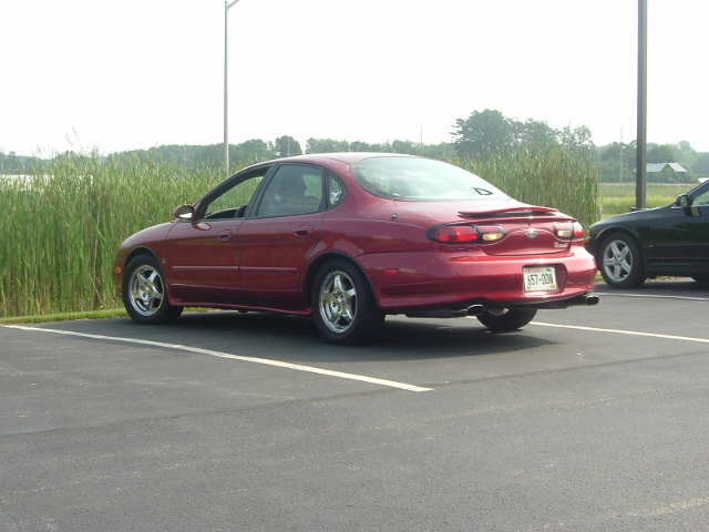 Red sedan, rear view. License plate 657-DON. Appears to be a 1996 Ford Taurus