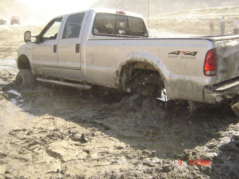 1977 Toyota Land Cruiser - Pickup truck is stuck in a muddy off-road area, with another vehicle in the distance.