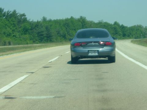 1993 Ford Taurus - Rear view of a 1993 Ford Taurus driving on a highway under a clear sky.