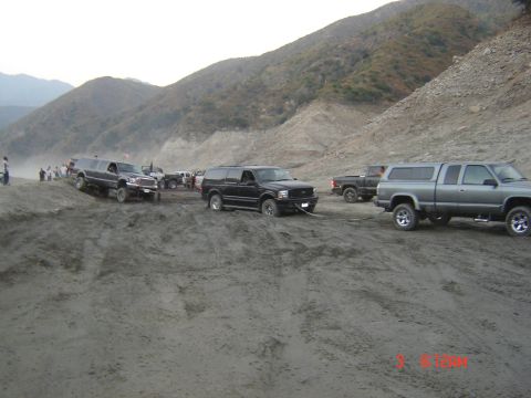 1977 Toyota Land Cruiser - Multiple off-road vehicles are stuck in a sandy terrain, with one vehicle attempting to tow another out.