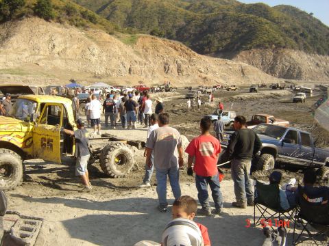 1977 Toyota Land Cruiser - Spectators and off-road vehicles gather at a muddy event in a hilly, dry landscape.