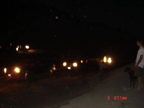 1977 Toyota Land Cruiser - A group of vehicles are seen at night with their headlights illuminated, while a person and dog stand nearby.