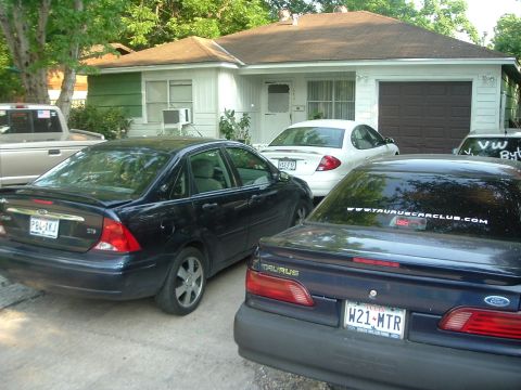 1993 Ford Taurus - A dark blue 1993 Ford Taurus is parked in front of a house with other vehicles.