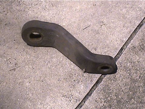 1978 Ford Bronco - A single automotive steering drag link part rests on a concrete surface.