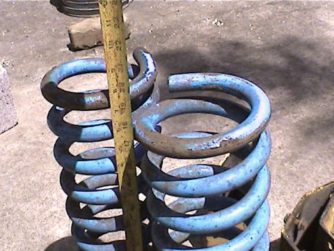 1978 Ford Bronco - A measuring tape is used to show the size of two blue suspension coil springs.