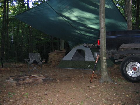 1976 GMC C/K Pickup - A campsite is set up with a tent, tarp, and a pickup truck parked nearby.