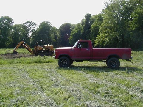 1978 Ford F-150 - A red 1979 Ford F-150 pickup truck is parked in a field with a backhoe in the background.