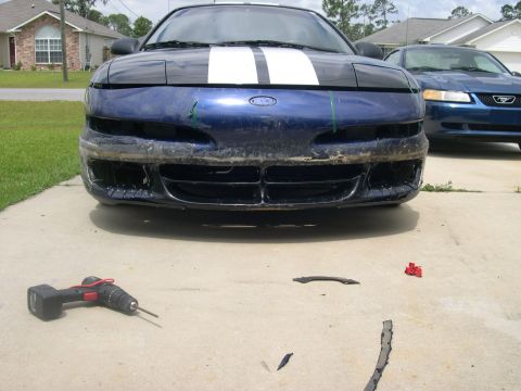 1997 Ford Probe - The front bumper of a blue 1997 Ford Probe has been removed, revealing the grille and headlights. A drill and detached bumper parts are on…
