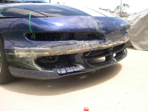 1997 Ford Probe - Front bumper of a 1997 Ford Probe shows significant damage and repair attempts.