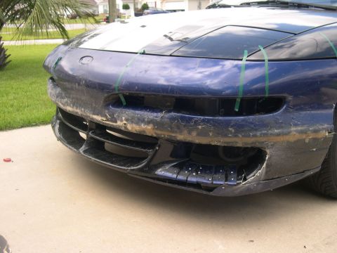 1997 Ford Probe - The front bumper of a blue car is shown, with visible damage and repair attempts using green tape.