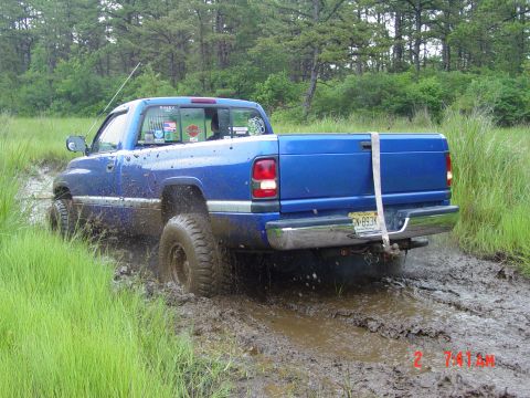 1995 Dodge 1500 - This blue pickup truck, likely from the late 1990s, is struggling to navigate through a muddy terrain.