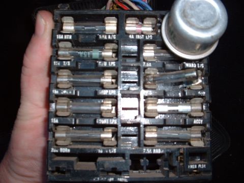 1978 Ford Mustang II - A hand holds a vehicle's fuse box, showing multiple fuses and their labels.