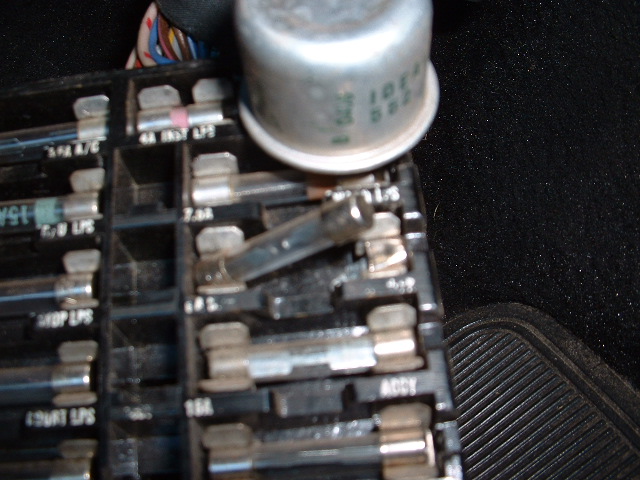 Close-up of under-dash fuse panel with glass tube fuses and circuit labels