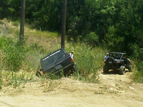 1986 Ford Bronco - A Jeep Cherokee XJ is stuck off-road while a side-by-side UTV waits nearby.