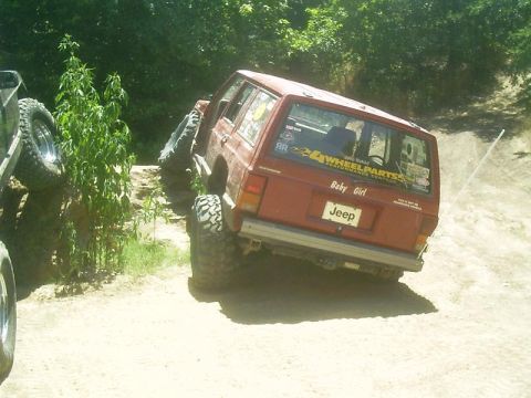 1986 Ford Bronco - Off-road Jeep Cherokee with 'Baby Girl' decal navigates a steep, sandy incline.