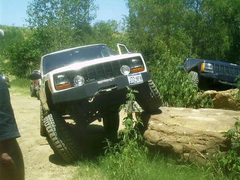 1986 Ford Bronco - A white Jeep Cherokee XJ is shown off-roading, with another Jeep visible in the background.