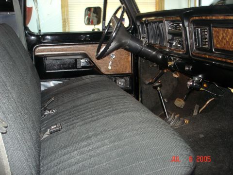 1979 Ford F-250 - The interior of a 1979 Ford F-250 features wood-grain trim and a bench seat.