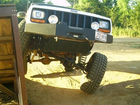 1986 Ford Bronco - A white Jeep is shown with a modified bumper and tires, with its front passenger wheel turned sharply.