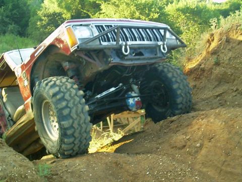 1986 Ford Bronco - This heavily modified Jeep Cherokee is tackling a steep dirt incline, its off-road capabilities.