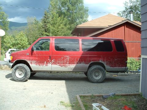 1994 Ford E350 - Red Ford E350 van modified with larger tires and suspension sits outside a house.