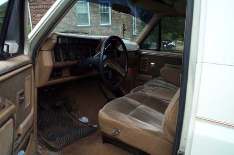 1985 Ford Bronco - The interior of this 1985 Ford Bronco features a tan dashboard, steering wheel, and plush seating.