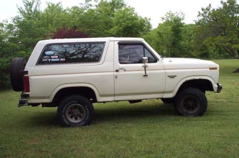 1985 Ford Bronco - Side profile of a white Ford Bronco, showing its classic SUV body style and exterior details.