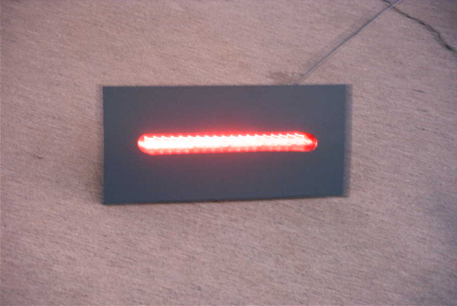 Gray panel with a horizontal slot glowing with a bright red illuminated LED bar