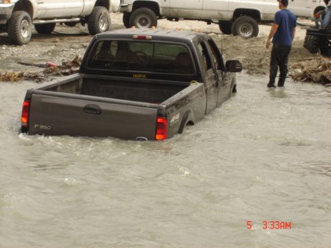 1977 Toyota Land Cruiser - A Ford F-350 pickup truck is stuck in floodwaters, with other vehicles nearby.