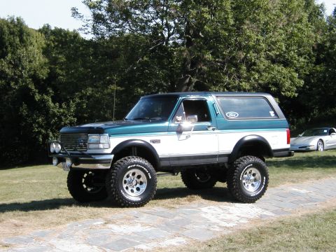1994 Ford Bronco - Lifted 1990s Ford Bronco parked outdoors with a Chevrolet Corvette in the background.