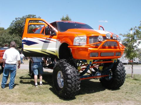 1994 Ford Bronco - Customized pickup truck with extreme lift and off-road tires on display.