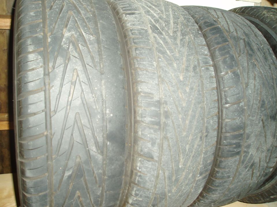 Stack of used performance tires on their sides showing directional V-tread, dusty and aged