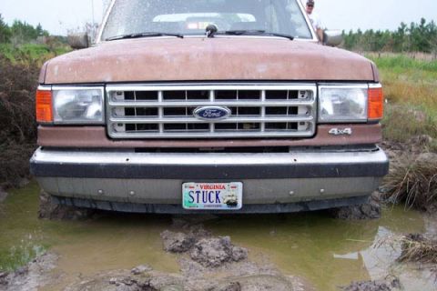 1988 Ford Bronco - This Ford truck is stuck in the mud, with its front tires submerged in water and dirt.