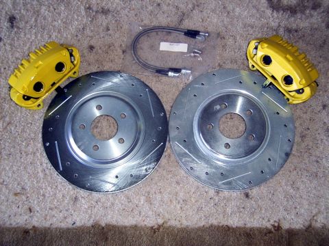 2002 Ford Mustang - Aftermarket brake components, including rotors and calipers, are laid out on a carpeted surface.